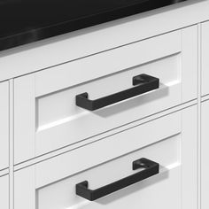 a white cabinet with black handles and drawers