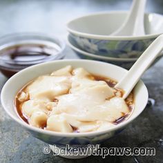 a bowl of dumplings with chopsticks sitting on a table next to two bowls