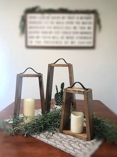 two wooden lanterns sitting on top of a table with greenery and candles in them