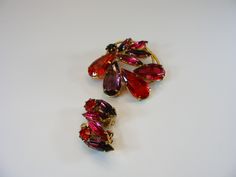 Red brooch, jewelry set, earrings brooch, earrings, pink earrings, crystals glass, round brooch, vintage brooch, vintage brooch pin, brooch, wedding brooch, costume jewelry, red crystal, --------------------------- A lovely, Edwardian style jewelry set. In a gold tone metal, this leaf shaped set has pink, red and amethyst look accent stones. This set includes a brooch and clip on earrings The brooch  is about 1.6"(4 cm) diameter,  with a locking pin. It is in very good condition. Pin is secure. Pink Brooch Jewelry For Evening, Pink Evening Jewelry Brooch, Pink Evening Brooch Jewelry, Red Round Brooch Jewelry, Red Costume Jewelry Brooch, Red Brooch For Jewelry Making, Vintage Brooches With Matching Earrings For Gift, Red Brooch, Color Stones Jewelry