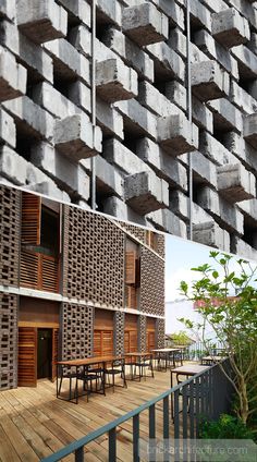 the building is made out of concrete blocks and has wooden tables in front of it