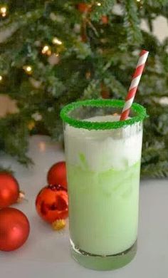 a green and white drink with a straw in it next to some christmas tree ornaments