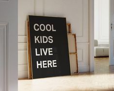 a black and white sign that says cool kids live here in front of an open door