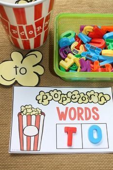 a table topped with lots of different types of letters and numbers next to a bowl of popcorn