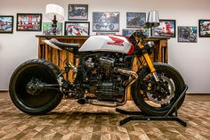 a white and red motorcycle sitting on top of a hard wood floor next to pictures