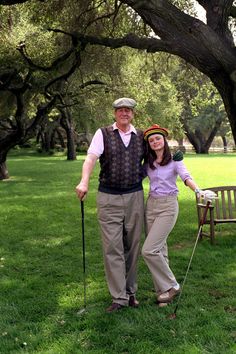 an older man and young woman standing in the grass with canes on their heads