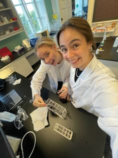 two women in white lab coats sitting at a table