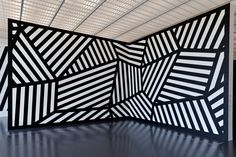 an abstractly designed room with black and white stripes on the wall, in front of a ceiling