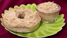 two donuts on a green plate with a cup of peanut butter