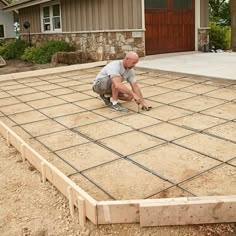 a man kneeling down on top of a cement slab in front of a house under construction