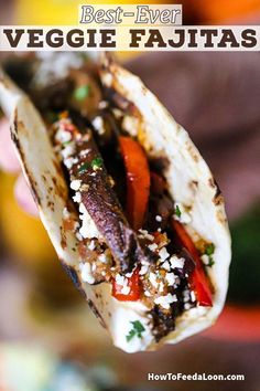 a hand holding a taco filled with meat and veggie fajitas