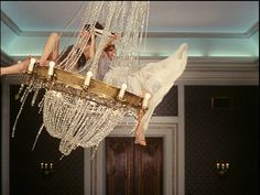 two people hanging upside down on a chandelier