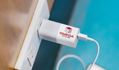 an electronic device plugged in to a wall next to a swimming pool with the omeba logo on it