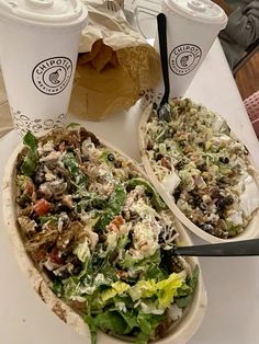 two plates filled with food and drinks on top of a white table next to each other