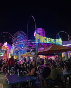 an amusement park at night with people eating and drinking