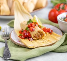 an enchilada on a plate with tomatoes and other food items