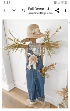 a wooden mannequin wearing overalls and a straw hat with flowers on it