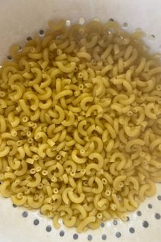 a white bowl filled with yellow noodles on top of a table