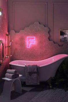 a bathroom with a pink bathtub and neon sign on the wall next to it