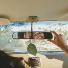 a person taking a photo in the rear view mirror of a car with their hands on the dashboard