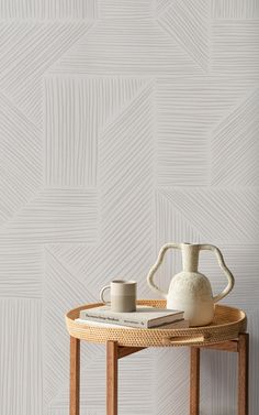 a white vase sitting on top of a wooden table next to a book and cup