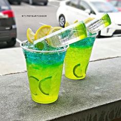 two glasses filled with lemonade and limeade sitting next to each other on a ledge