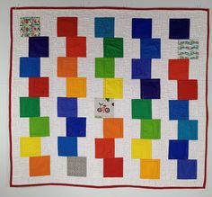 a quilted wall hanging with colorful blocks on it