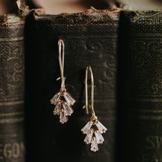 two pairs of earrings sitting on top of an old book with the pages in front of them