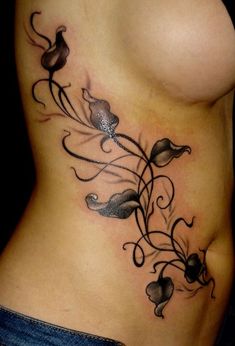 a woman's stomach with flowers and swirls on the side, tattoo style