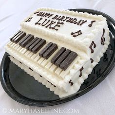 a birthday cake that is shaped like a piano keyboard on a black plate with white frosting