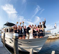 a group of people standing on top of a boat in the water with their arms up