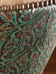 an ornate green and brown vase sitting on top of a wooden table