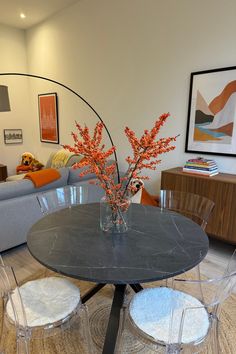 a glass table with chairs around it in a living room area next to a couch