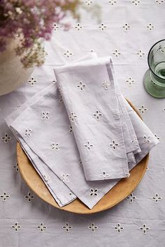 four napkins on a plate next to a vase with flowers