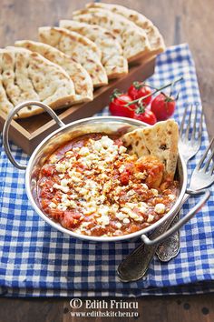 a bowl of food with bread and tomatoes on the side