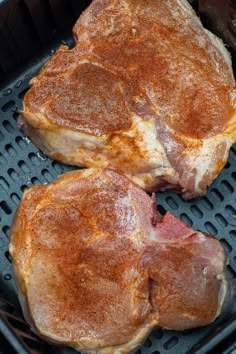 two steaks are cooking on the grill in an open air frying pan,