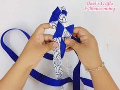 two hands are holding an origami piece with blue ribbon and white paper on it