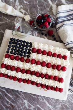 an american flag cake is decorated with berries and icing on a marble table top