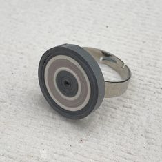 a black and white ring with a gray center sits on the floor next to a piece of paper