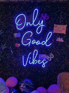 a neon sign that says only good vibes in front of balloons and other decorations