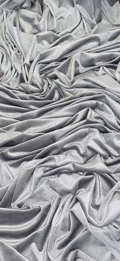 an image of a bed that is made up with silver sheets and blankets on it