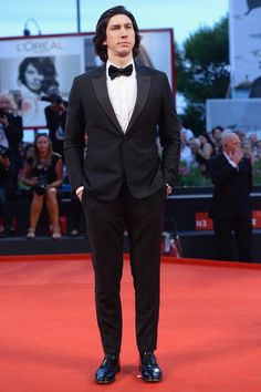 a man in a tuxedo standing on a red carpet