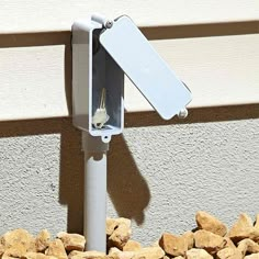 a white street sign sitting on the side of a building next to rocks and gravel