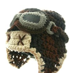 a crocheted hat with an eye patch on the front and ear flaps