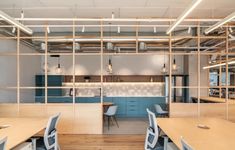 an office with wooden desks and chairs in front of a counter top area that has shelves on the wall