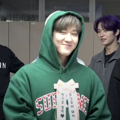 three young men standing next to each other in front of lockers wearing green hoodies