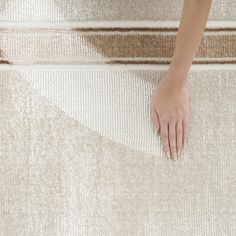 a woman's hand is on the edge of a carpeted stair case, with her left foot resting on it