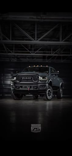 a large black truck parked in a garage next to a metal structure with lights on