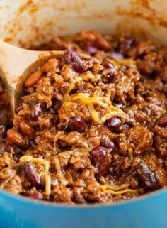 chili and beans in a blue pot with a wooden ladle scooping up some food