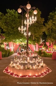 an outdoor wedding setup with candles and chandeliers on the centerpiece, surrounded by red rose petals